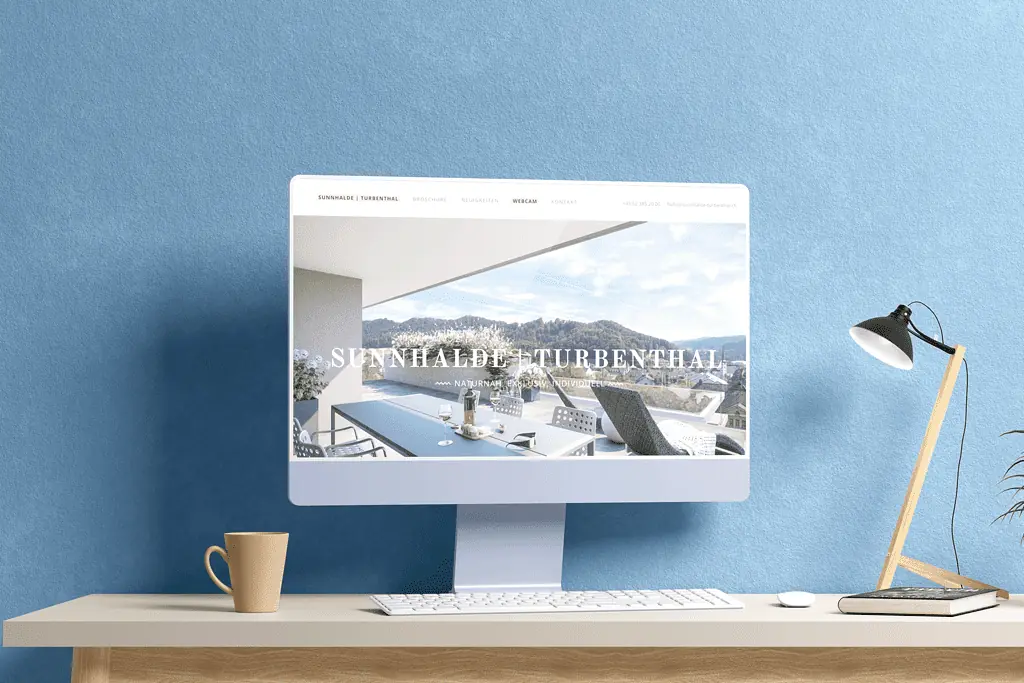 Auf einem Computerbildschirm mit blauem Hintergrund und einer Tasse Kaffee wird eine Immobilien-Website angezeigt.